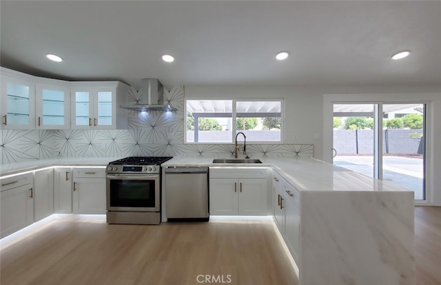 kitchen featuring white cabinets, stainless steel appliances, sink, and wall chimney exhaust hood