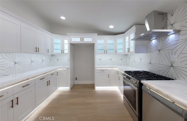 kitchen featuring white cabinets, decorative backsplash, stainless steel gas stove, and wall chimney exhaust hood