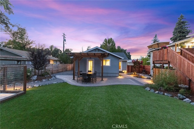 back house at dusk featuring a patio and a yard