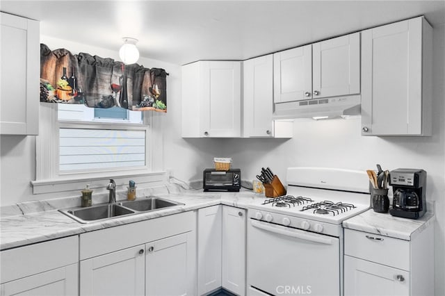 kitchen with white range with gas stovetop, light stone countertops, white cabinetry, and sink