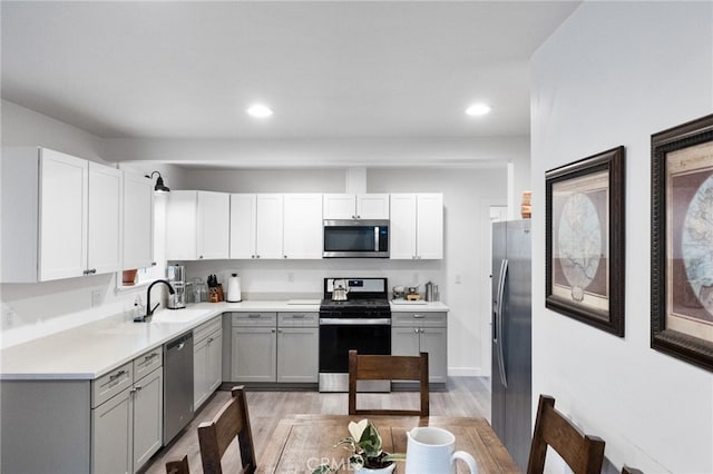 kitchen featuring gray cabinets, stainless steel appliances, light hardwood / wood-style flooring, and sink