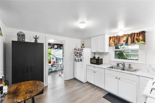 kitchen with a healthy amount of sunlight, light hardwood / wood-style floors, white cabinetry, and sink