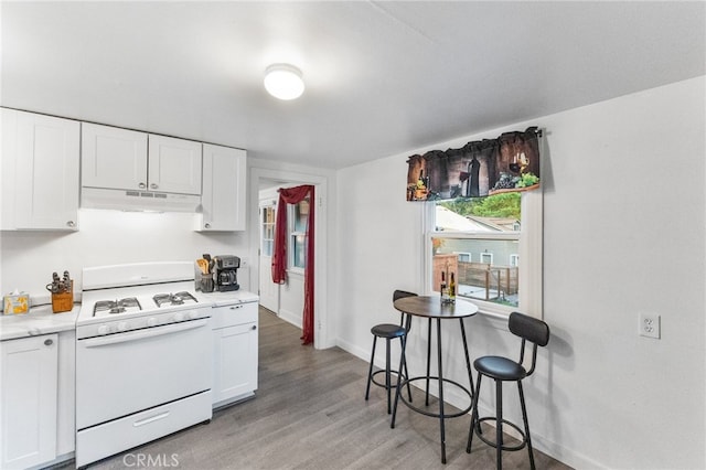 kitchen with white cabinetry, range hood, white gas range oven, and light hardwood / wood-style flooring