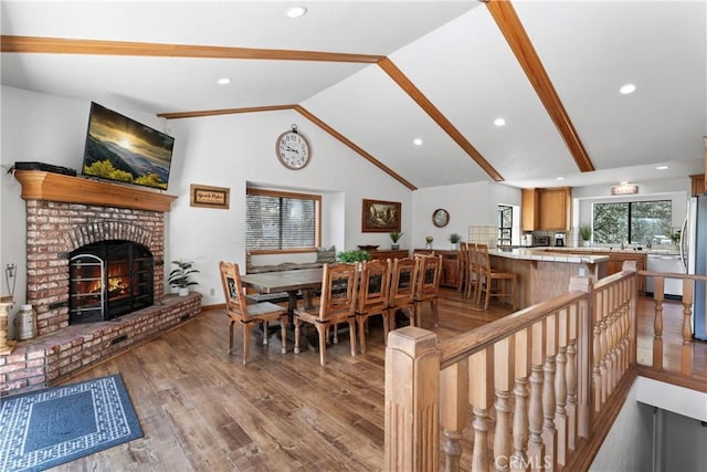 dining room with light wood-type flooring, lofted ceiling, and a fireplace