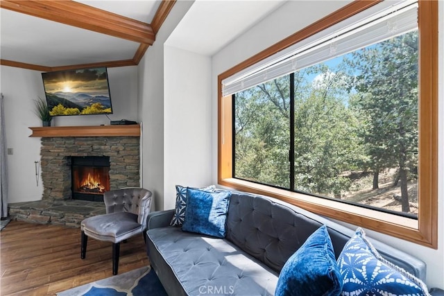 living room featuring beam ceiling, a stone fireplace, and hardwood / wood-style flooring