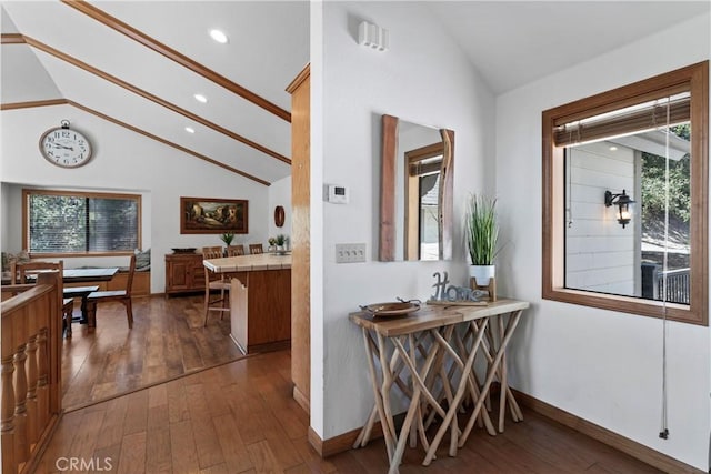 corridor with high vaulted ceiling, dark wood-type flooring, and a wealth of natural light