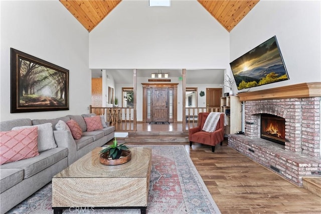 living room with wood-type flooring, high vaulted ceiling, a brick fireplace, and wood ceiling