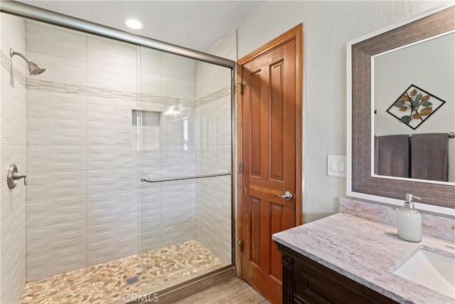 bathroom featuring hardwood / wood-style flooring, vanity, and an enclosed shower