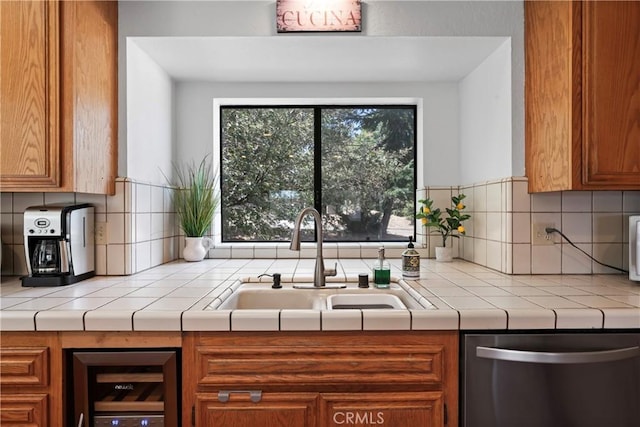 kitchen featuring tasteful backsplash, stainless steel dishwasher, beverage cooler, sink, and tile countertops