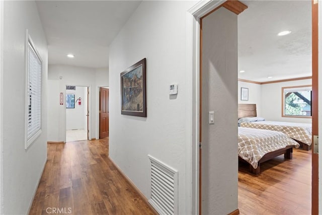 hallway with ornamental molding and hardwood / wood-style flooring