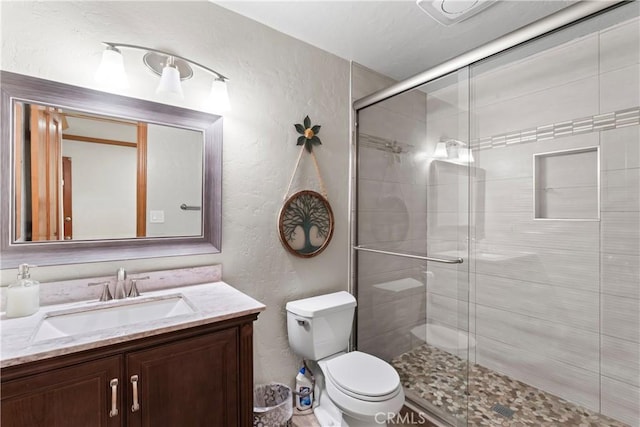 bathroom with an enclosed shower, vanity, and toilet