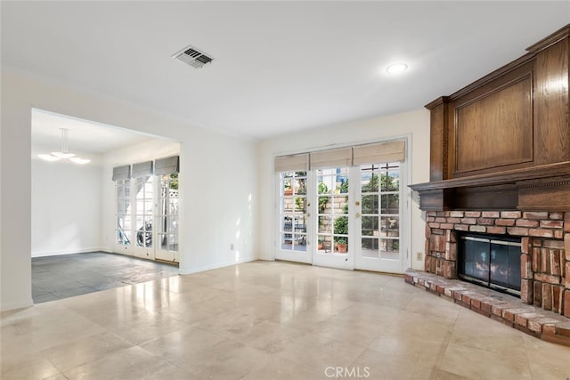 unfurnished living room with a fireplace, french doors, and a chandelier