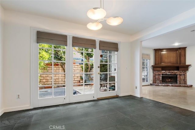 doorway to outside featuring a fireplace, a chandelier, and dark tile patterned floors