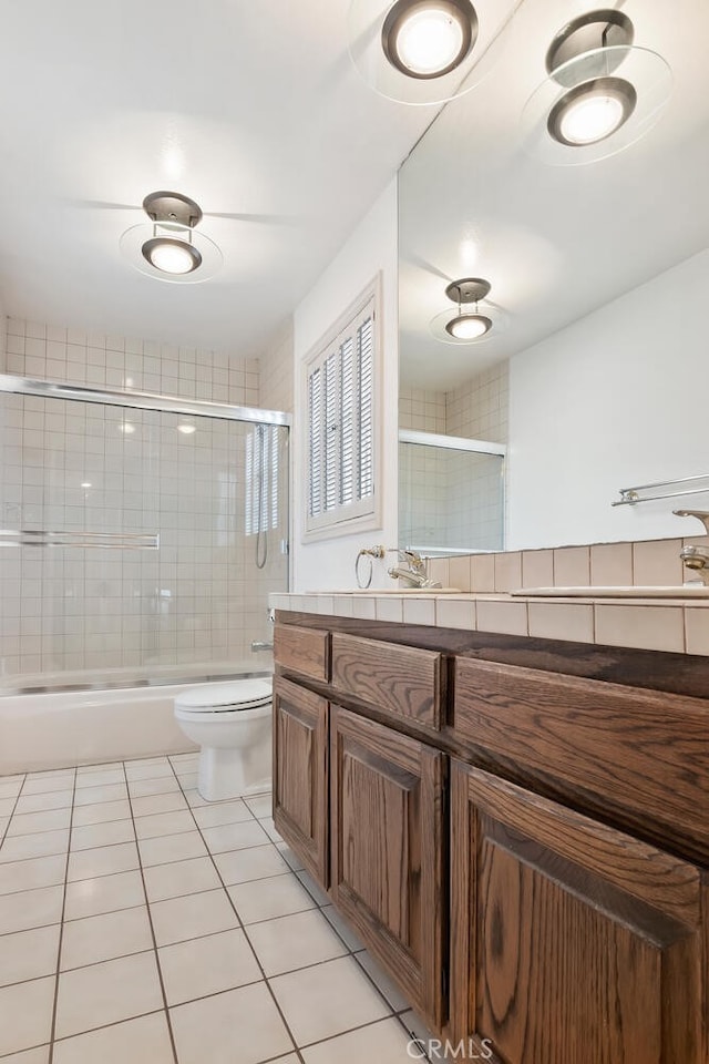 full bathroom featuring tile patterned flooring, vanity, toilet, and bath / shower combo with glass door