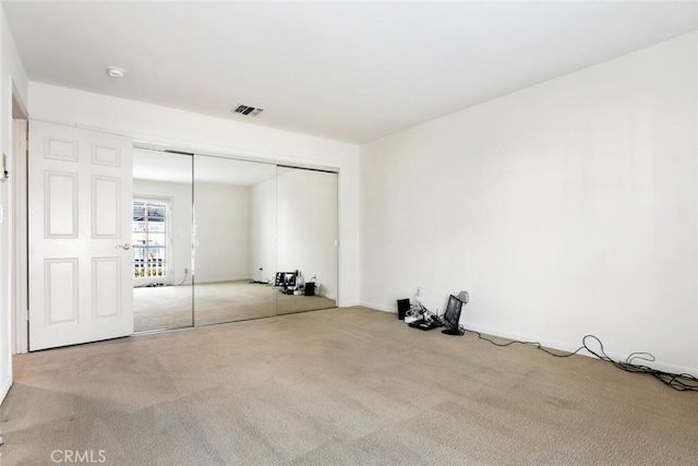 unfurnished bedroom featuring light colored carpet and a closet