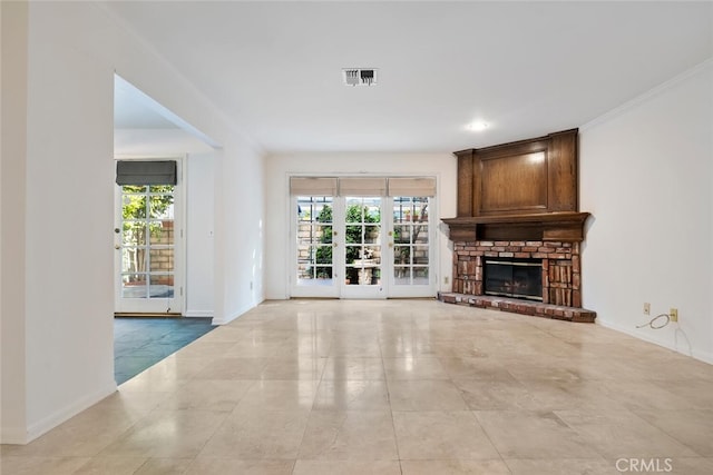 unfurnished living room featuring a large fireplace, crown molding, plenty of natural light, and french doors