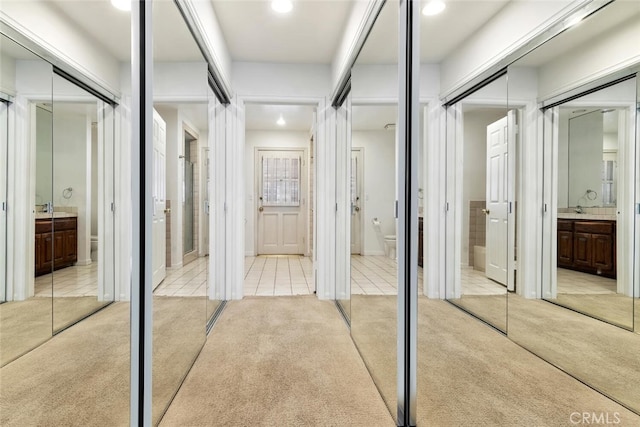 hallway featuring light colored carpet and sink