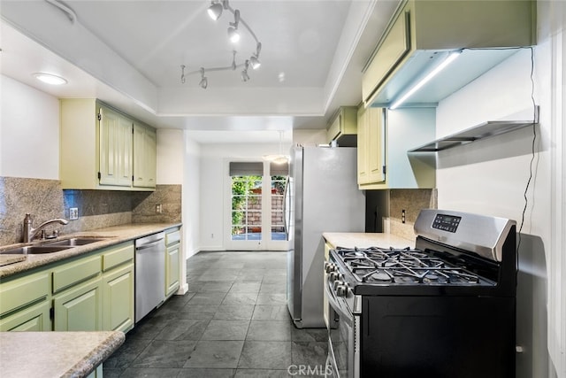 kitchen featuring sink, green cabinetry, decorative backsplash, a tray ceiling, and stainless steel appliances