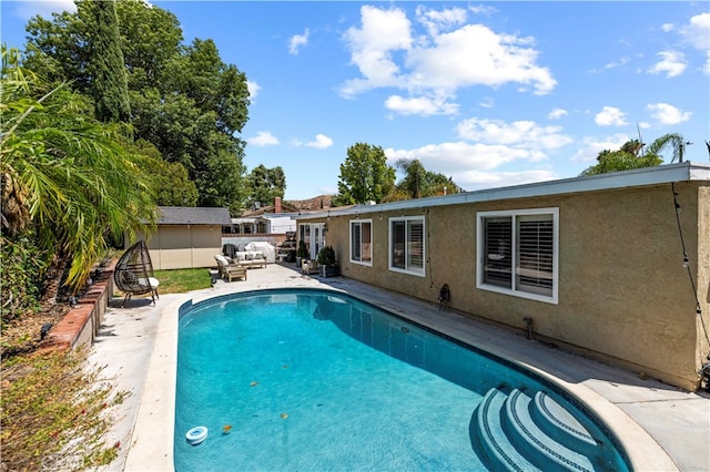 view of pool with a shed and a patio