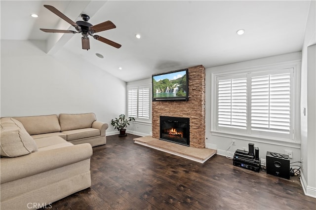 living room with dark hardwood / wood-style flooring, vaulted ceiling, ceiling fan, and a stone fireplace