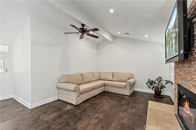 living room with vaulted ceiling with beams, a stone fireplace, dark wood-type flooring, and ceiling fan