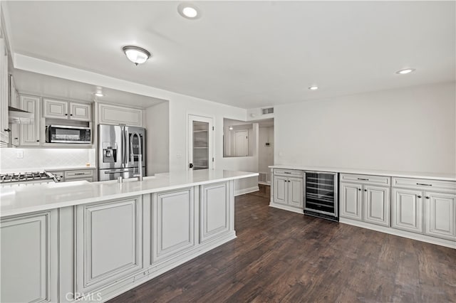 kitchen featuring wine cooler, appliances with stainless steel finishes, dark wood-type flooring, and decorative backsplash