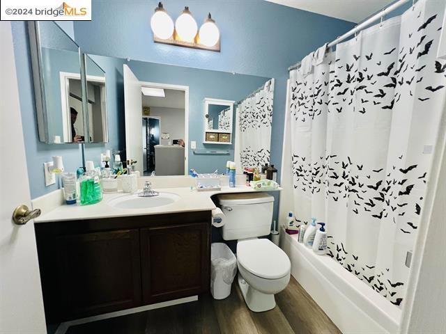 full bathroom with vanity, hardwood / wood-style floors, toilet, and shower / bath combo