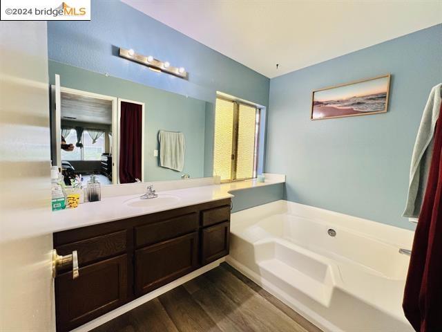 bathroom with a bathing tub, vanity, and wood-type flooring