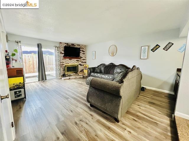 living room featuring a brick fireplace and light wood-type flooring