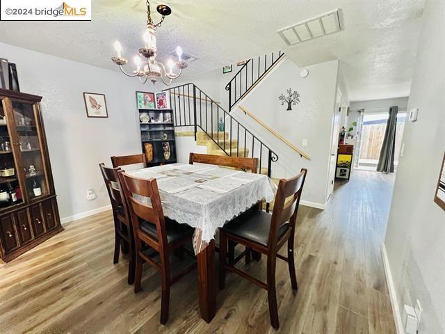 dining space featuring hardwood / wood-style flooring, a notable chandelier, and a textured ceiling