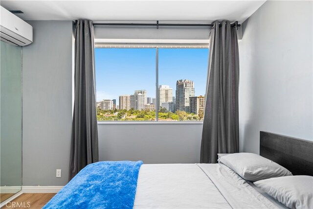 bedroom with hardwood / wood-style flooring and a wall mounted AC