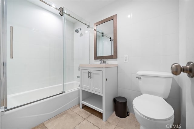 full bathroom with toilet, tile patterned flooring, vanity, tile walls, and enclosed tub / shower combo