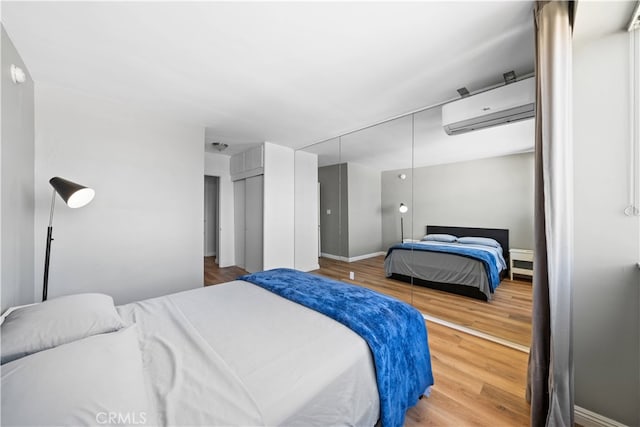 bedroom featuring a closet, wood-type flooring, and a wall unit AC