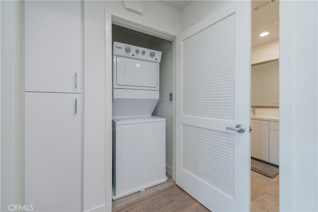 laundry room featuring stacked washer / dryer and light wood-type flooring