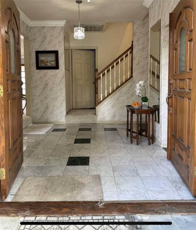 entryway with ornamental molding and an inviting chandelier