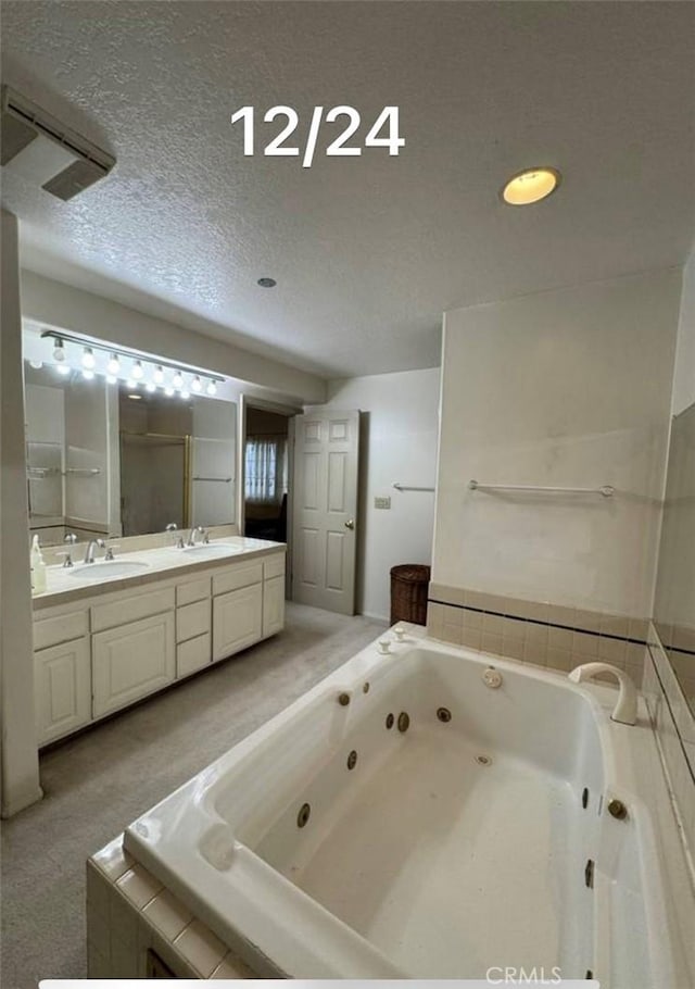 bathroom featuring tiled bath, vanity, and a textured ceiling