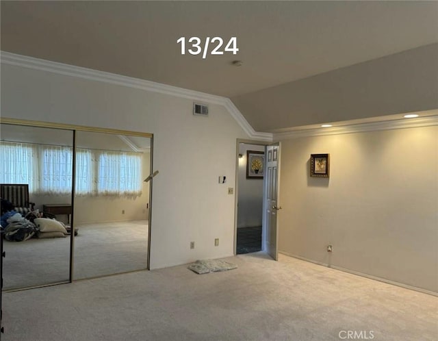 carpeted empty room featuring crown molding and lofted ceiling