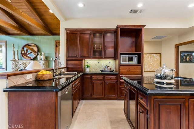 kitchen with decorative backsplash, visible vents, a peninsula, stainless steel appliances, and a sink