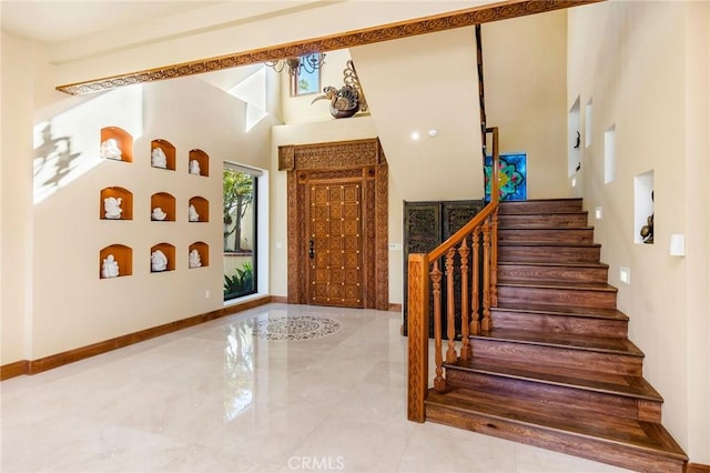stairway featuring a towering ceiling and baseboards