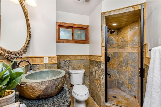 bathroom with tile walls, toilet, and walk in shower