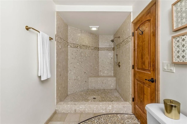 bathroom featuring tiled shower, toilet, and tile patterned floors