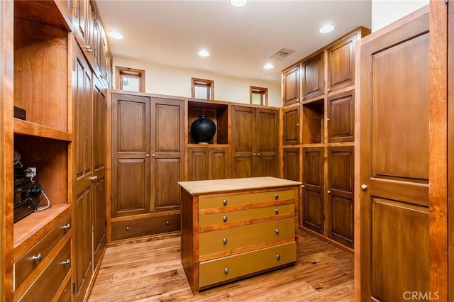 walk in closet with light hardwood / wood-style floors