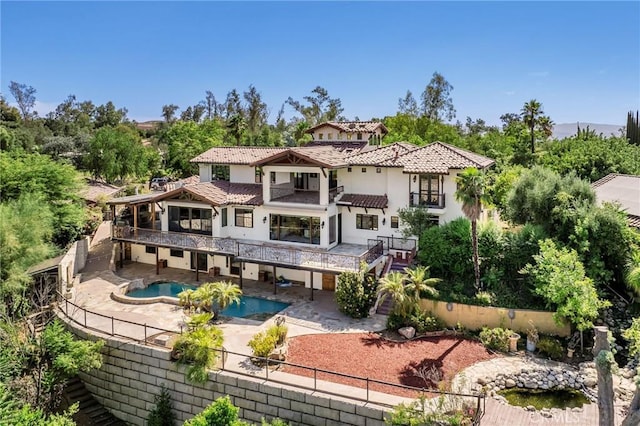 back of house featuring a balcony, a patio, and a swimming pool with hot tub