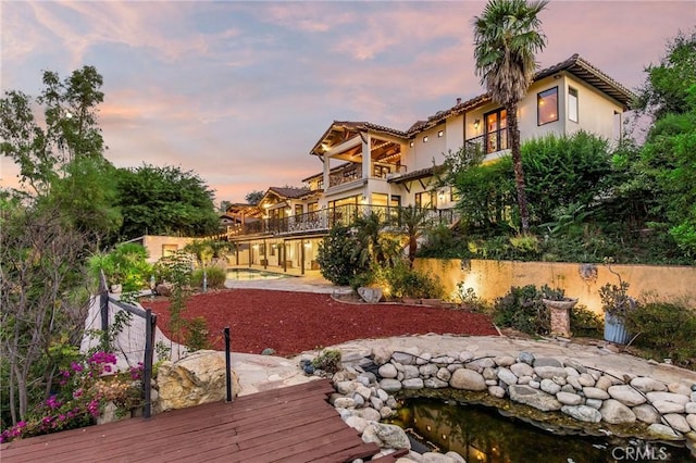 yard at dusk featuring a balcony and a patio area