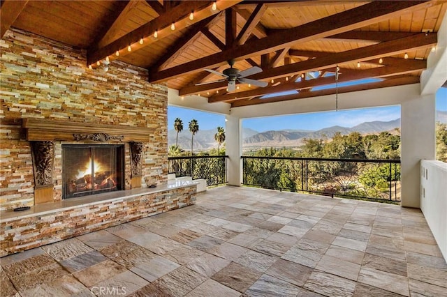 view of patio / terrace featuring a mountain view, an outdoor stone fireplace, and ceiling fan