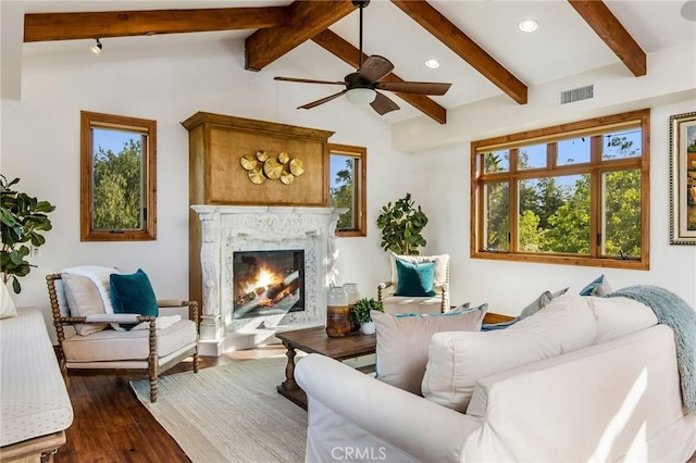 living room with a premium fireplace, ceiling fan, dark hardwood / wood-style floors, and lofted ceiling with beams