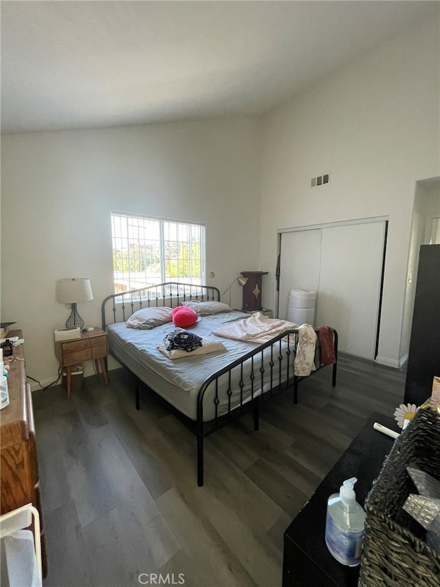 bedroom with high vaulted ceiling, a closet, dark hardwood / wood-style floors, and stainless steel fridge