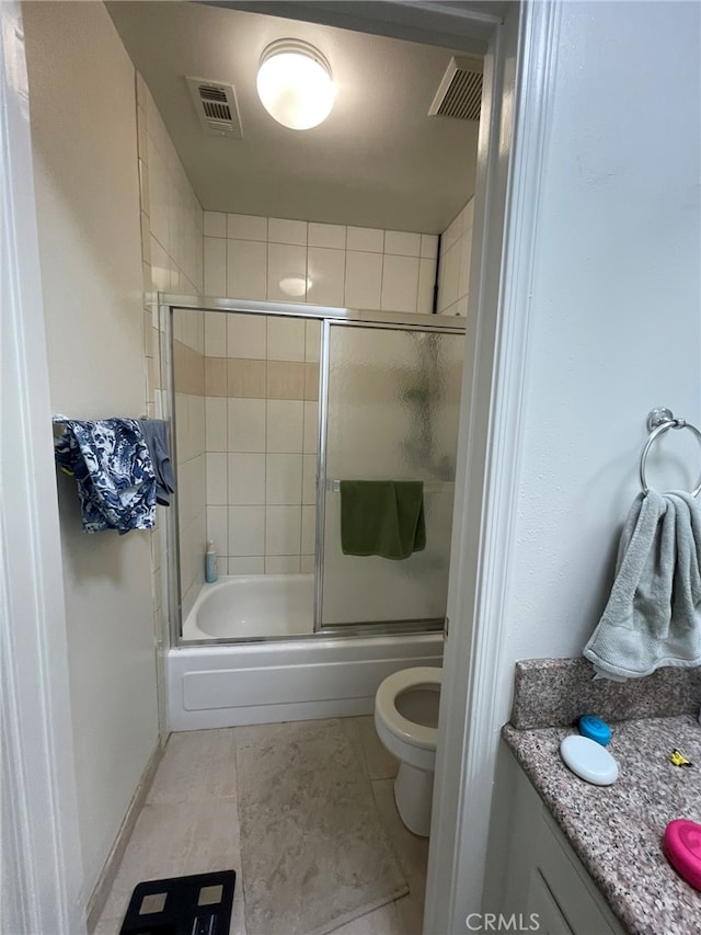 full bathroom with tile patterned floors, shower / bath combination with glass door, vanity, and toilet