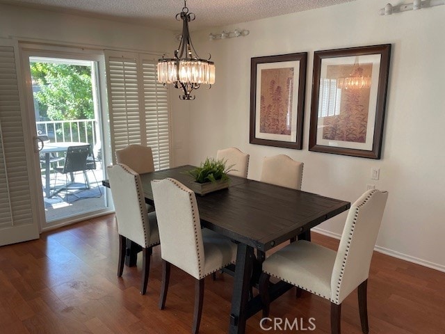 dining room with a notable chandelier, a textured ceiling, and dark wood-type flooring