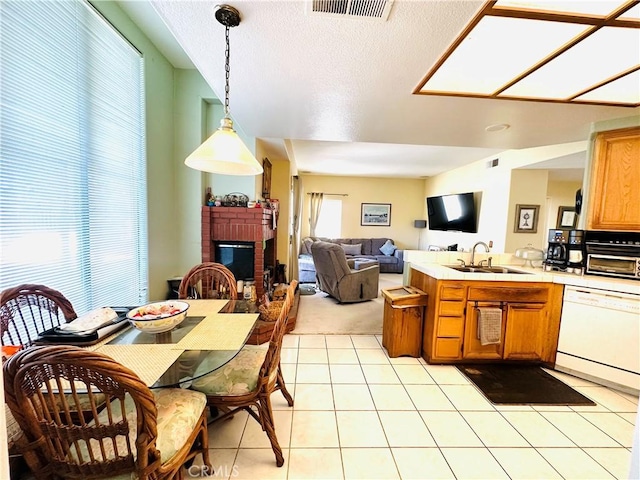 kitchen with dishwasher, sink, pendant lighting, a fireplace, and light tile patterned floors